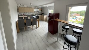 Una cocina moderna con comedor, un refrigerador rojo y una ventana con vistas al campo.