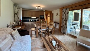 Un saló agradable amb un sofà, una taula de centre de fusta i una zona de menjador amb cadires i una taula.