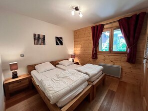 Une pièce aux murs lambrés, comprenant un lit, une table de chevet, une lampe et une fenêtre avec des rideaux.