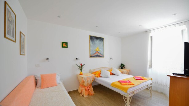 A bedroom with a bed, a sofa, a small table with a plant, and a painting on the wall. - A1 - apt in the Very Heart of Split With sea View (Split)