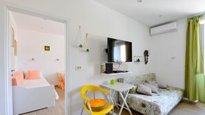 A compact living space with a bed, a sofa, a small table, a TV, and an air conditioning unit. - A1 - apt in the Very Heart of Split With sea View (Split)