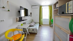 A compact living space with a sofa, a TV, a small table, and a chair. - A1 - apt in the Very Heart of Split With sea View (Split)