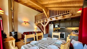 L’intérieur chaleureux d’un chalet comprend un coin repas, une cuisine et un escalier en bois.