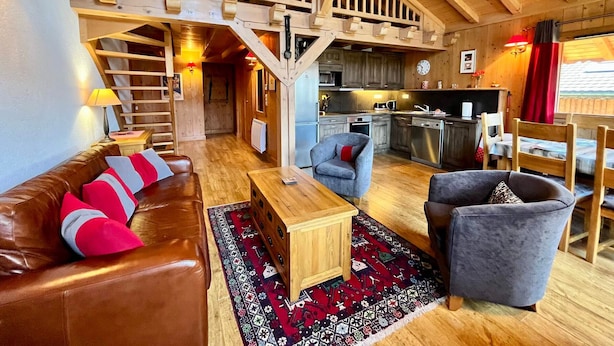 Un vaste espace de vie aménagé dans un style industriel, avec un escalier en bois, une cuisine et un coin repas.