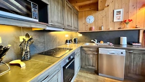 Une cuisine moderne avec des meubles en bois, un lave-vaisselle en acier inoxydable et une horloge au mur.