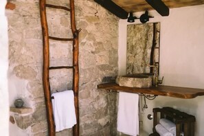 A rustic bathroom with a stone wall, wooden ladder, and a wooden shelf with a sink and towel rack. - Lovely Cottage With sea Views in Selca, Croatia (Selca)