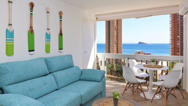 A balcony with a view of the sea, a blue sofa, and a table with chairs. - La Oca 9-2 (Benidorm)