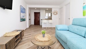 A modern living room with a blue sofa, a coffee table with a plant, and a TV mounted on the wall. - La Oca 9-2 (Benidorm)