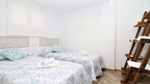 A room with two beds, each with a floral-patterned bedspread, a wooden ladder, and a white ceiling. - La Oca 9-2 (Benidorm)