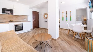 Eine moderne Küche mit weißen Schränken, einer Holzarbeitsplatte und einem eingebauten Backofen. Es gibt einen Essbereich mit einem runden Tisch und weißen Stühlen.