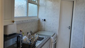 A compact kitchen with white cabinets, a built-in oven, a sink, and a window above the countertop.