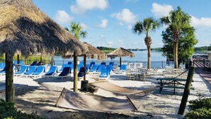 A beach with thatched umbrellas, blue lounge chairs, and palm trees. - Chic Disney Condo/w Fireplace at Bahama Bay Resort 15 mins from Disney  (Davenport)