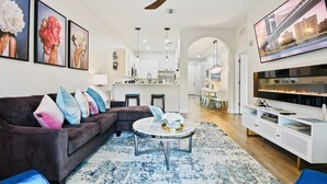 A modern living room with a dark brown sofa, a round coffee table, and a large flat-screen TV. - Chic Disney Condo/w Fireplace at Bahama Bay Resort 15 mins from Disney  (Davenport)