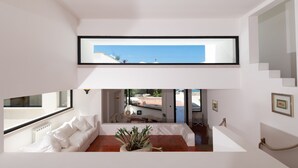 Interior moderno com uma janela ampla, paredes brancas, um sofá branco e vista para o exterior.