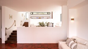 Uma sala de estar moderna com escada, um sofá branco e uma mesa de centro.