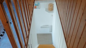 Una escalera de madera con una pared blanca y una pequeña mesa con una cesta.