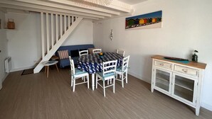 Un comedor con una mesa y sillas, una escalera, un armario y un cuadro en la pared.