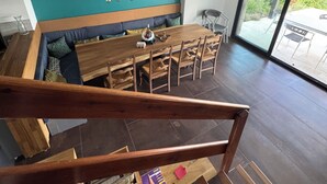 Un intérieur moderne avec une table à manger en bois, un canapé bleu et un escalier menant à un balcon.