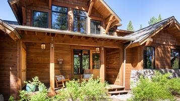 Une cabane en bois dotée d’une véranda, de grandes fenêtres et d’un mur en pierre.