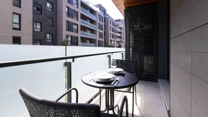 A balcony with a table set for two, overlooking a modern apartment building.