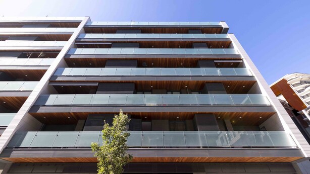 A multi-story building with a modern architectural design, featuring balconies and large windows.