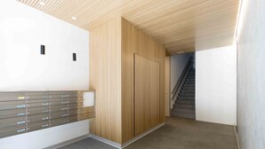 A modern lobby with a wooden panel wall, a metal mail slot, and a staircase.