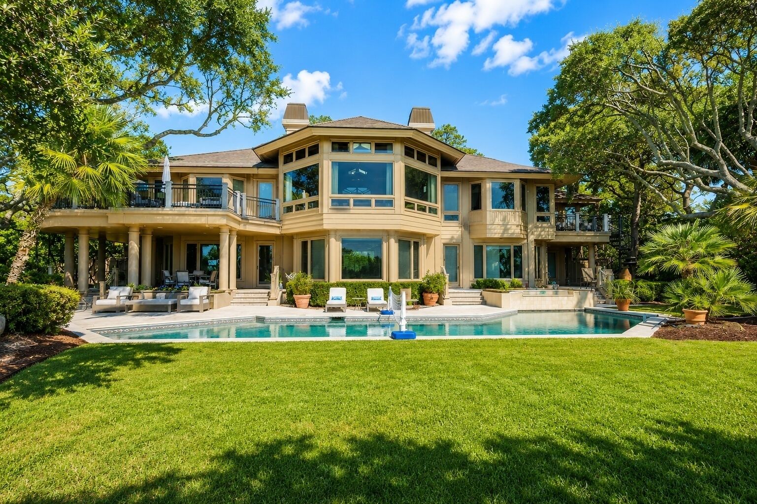 A large, multi-story house with a swimming pool in the front yard.