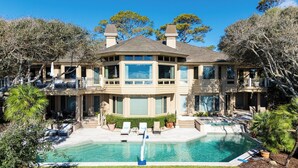 Un'ampia casa a due piani con piscina, diversi balconi e un giardino curato.