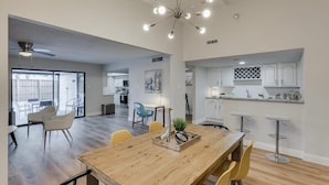 Amplia sala de estar con una mesa de comedor de madera, sillas amarillas y una lámpara de techo moderna.