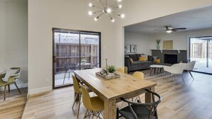 Un salón amplio con una mesa de comedor de madera, sillas amarillas, una chimenea y un ventilador de techo.