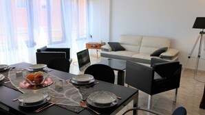 A dining area with a table set for four, a sofa, and a lamp in a living room. - Your central and comfortable 100 sqm flat in Valencia City. 10 Gigabit internet (Valencia)