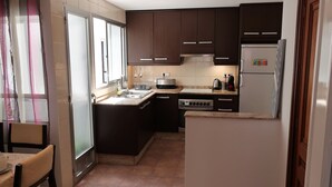 A compact kitchen with dark cabinets, a stainless steel stove, and a refrigerator. - Your central and comfortable 100 sqm flat in Valencia City. 10 Gigabit internet (Valencia)