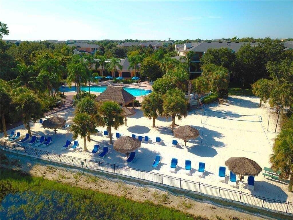 Ein Resort mit Schwimmbad, Strandbereich inklusive Liegestühle und Sonnenschirme sowie ein eingezäunter Poolbereich.