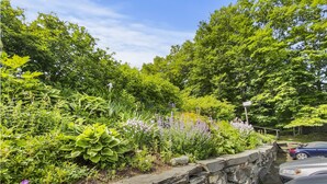 A stone wall with a garden featuring various plants and flowers. - 208 Village Gate Studio Bedroom Condo by RedAwning (Warren)