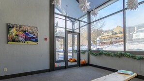 A room with a large window, a door, a painting, and a bench. - 208 Village Gate Studio Bedroom Condo by RedAwning (Warren)