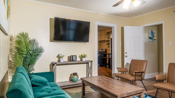 A living room with a teal sofa, a wooden coffee table, and a ceiling fan.