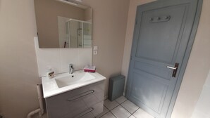 Casa de banho com lavatório branco, espelho, toalheiro e porta azul.