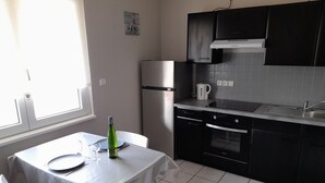 Cozinha compacta com área de refeições, com geladeira, fogão, pia e mesa posta para dois.