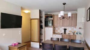 A compact living space with a kitchenette, a dining area, and a TV mounted on the wall. - Résidence Lalbane - Piscine - Vars Les Claux (Vars)