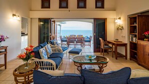 A spacious living area with a view of the ocean, furnished with sofas, a coffee table, and a dining set. - Villa Azure Rose - Coral Estate (Curaçao)