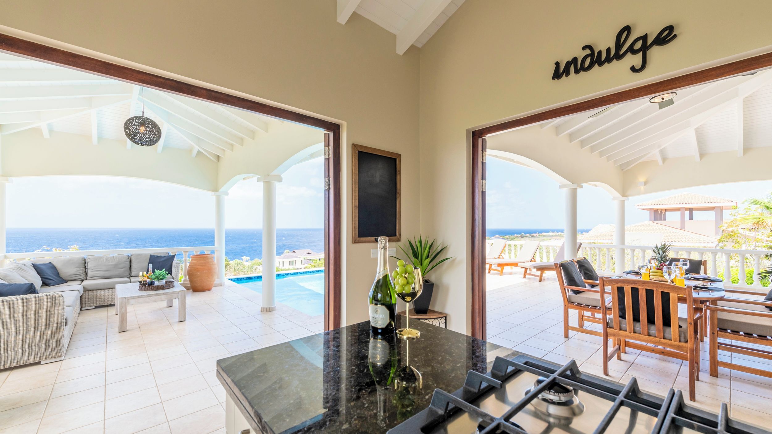 A spacious patio area with a pool, outdoor seating, and a view of the ocean.