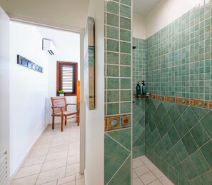 A bathroom with green tiles, a shower, and a toilet. - Villa Sundara - Coral Estate (Curaçao)