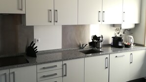 A modern kitchen with white cabinets, a granite countertop, and stainless steel appliances. - Lisbon Grand View (Lisboa)