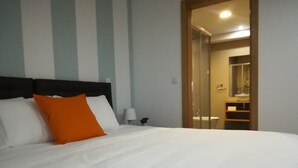 A hotel room with a large bed, a nightstand, a lamp, and a bathroom visible through an open door. - Lisbon Grand View (Lisboa)