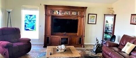 A living room with a large wooden entertainment center, a leather sofa, and a coffee table.