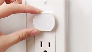 Mão pressionando um interruptor numa tomada elétrica branca.