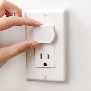 Una mano pulsando un interruptor en un enchufe blanco.