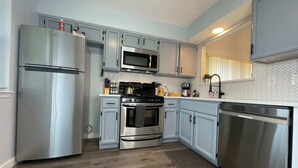 Uma cozinha moderna com eletrodomésticos de aço inoxidável, armários azul-claros e um mosaico de backsplash em padrão herringbone.