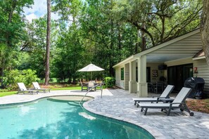 A swimming pool with lounge chairs and a covered patio area.