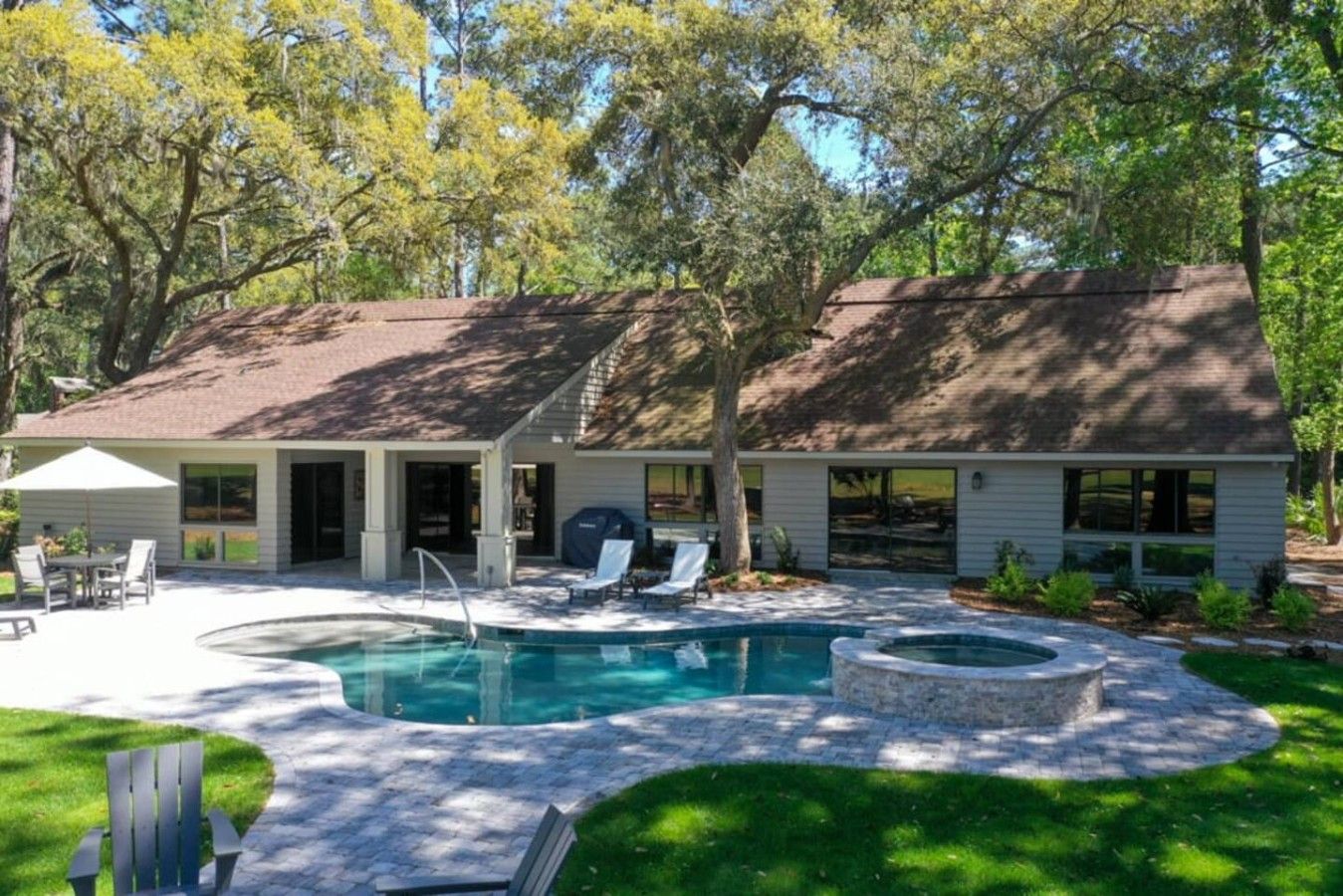 Ein Haus mit Swimmingpool, Sitzgelegenheiten im Freien und einer überdachten Terrasse.